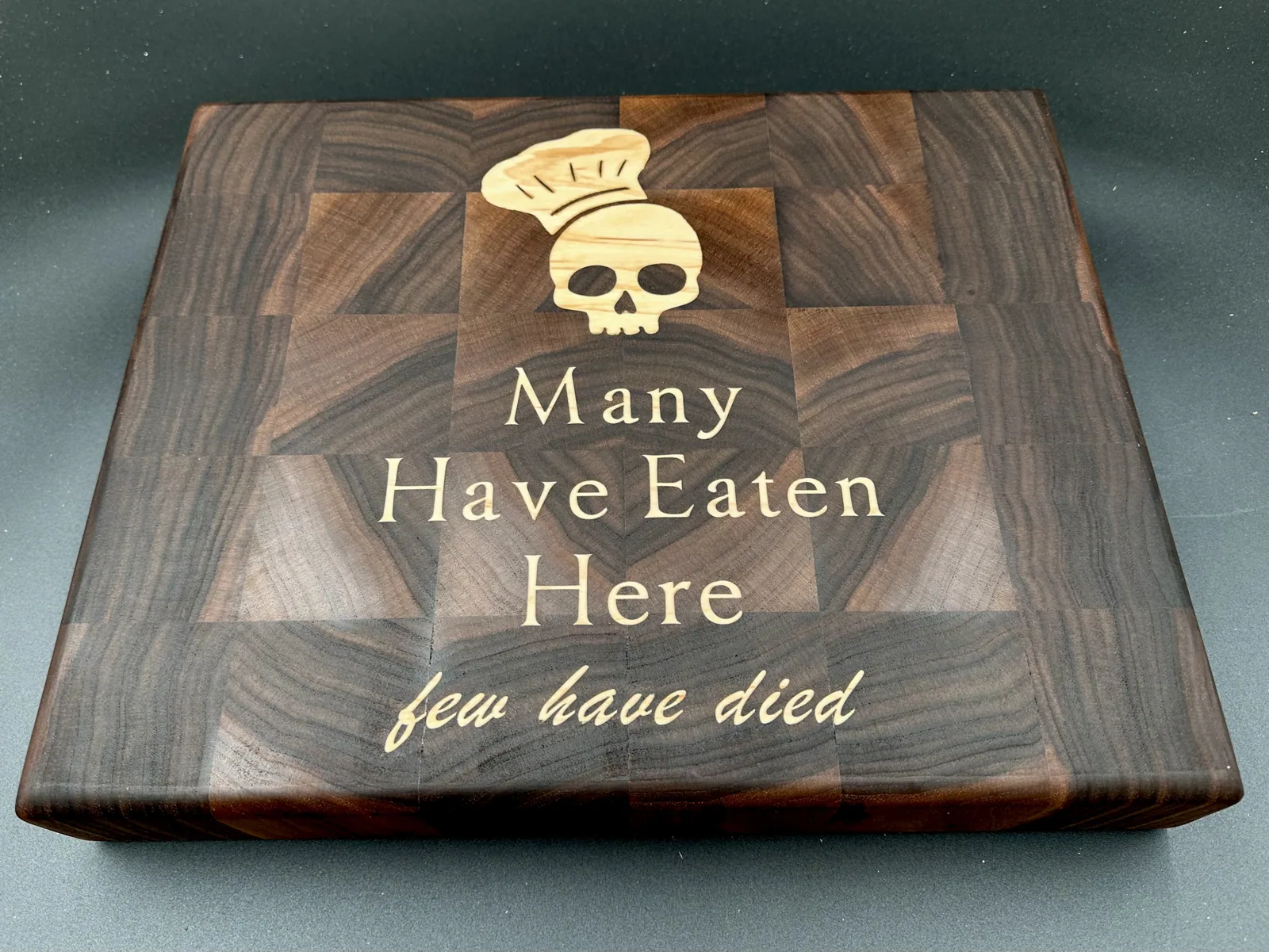 Finished end-grain walnut cutting board with a maple chef's-skull inlay