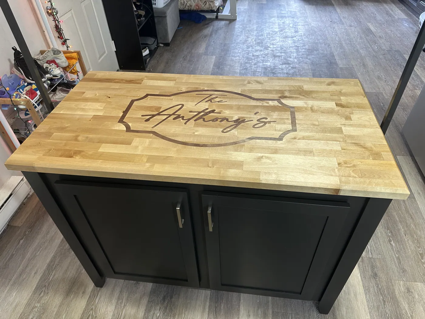 Butcher-block island with a maple top engraved with the family name, on a black shaker base.