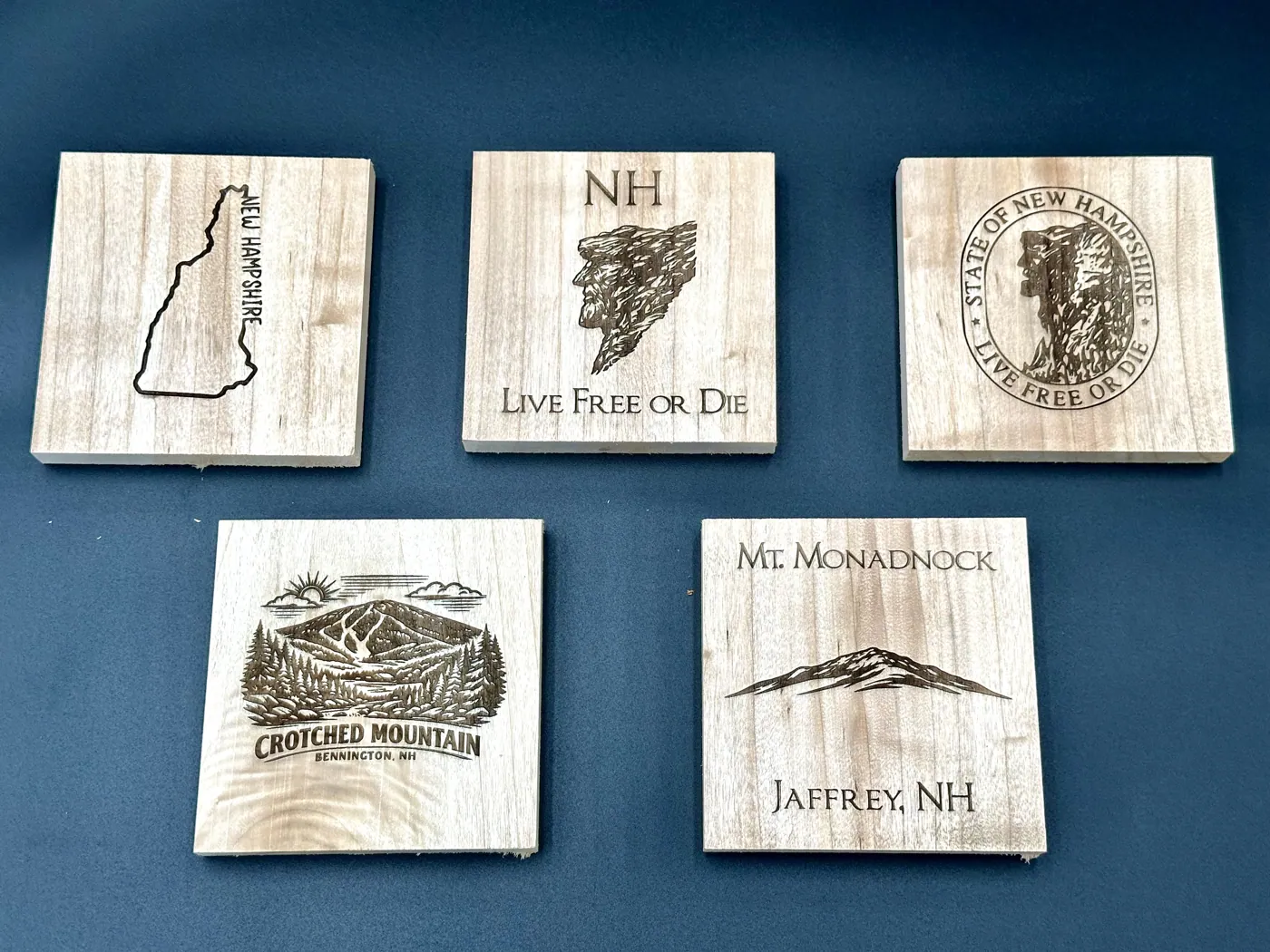 Maple coasters engraved with New Hampshire landmarks and mottos.