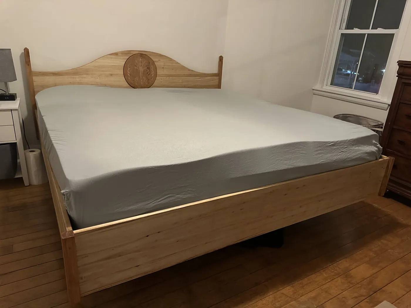 Bed frame with an arched headboard and a hand-carved Tree of Life medallion at its center.