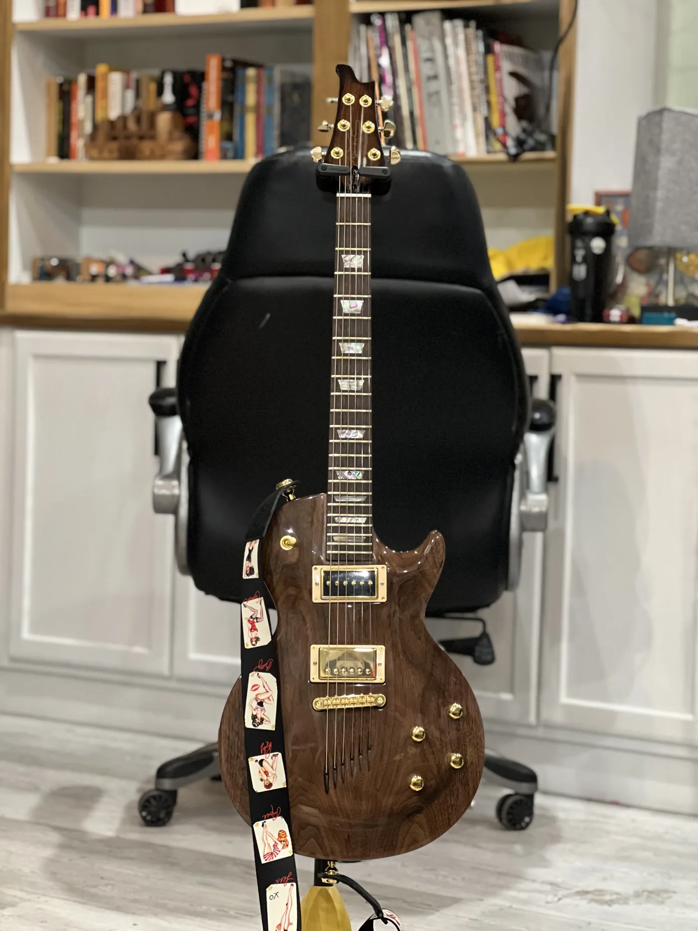 Solid-body electric guitar in figured walnut with gold hardware and pearl inlays.