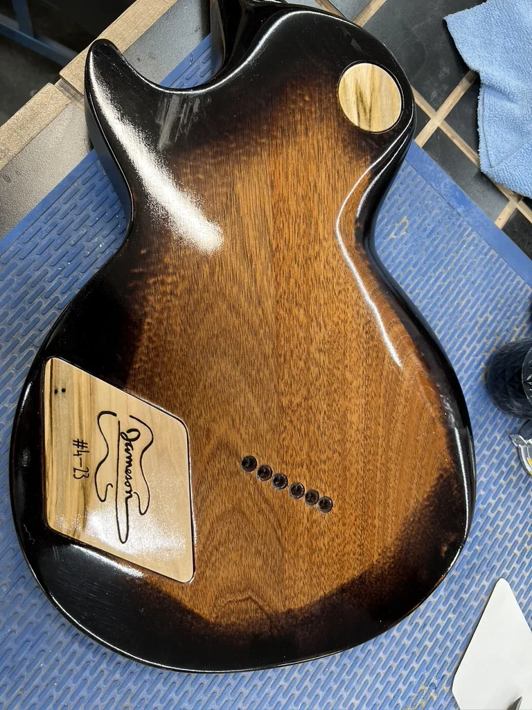 The finished custom maple Les Paul style guitar on a stand