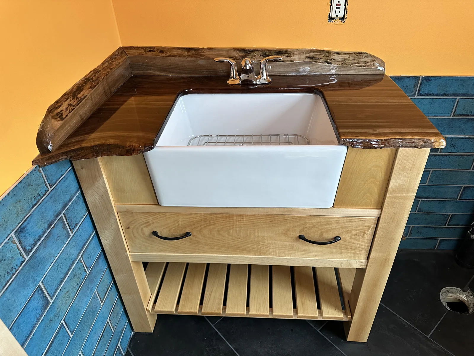 Finished maple and walnut vanity with a porcelain farmhouse sink installed in the bathroom